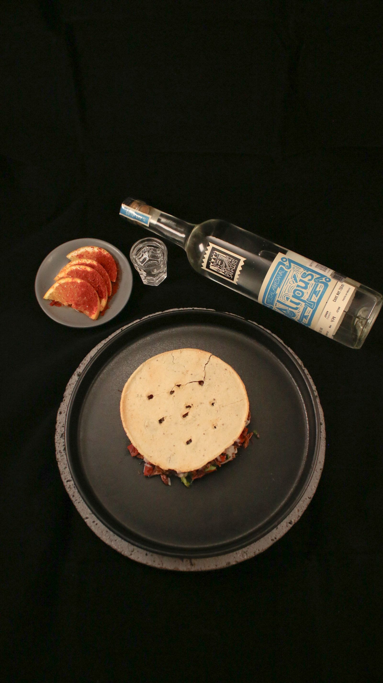 Illustrative tabletop photograph of a Mexican taco, grapefruit and mezcal